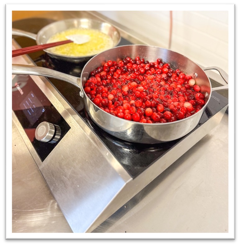 Cranberries and butter in pans on a cooktop